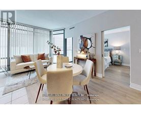 A dining room with a table set for two and a couch with pillows.