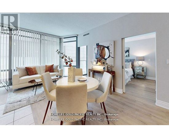 A dining room with a table set for two and a couch with pillows.