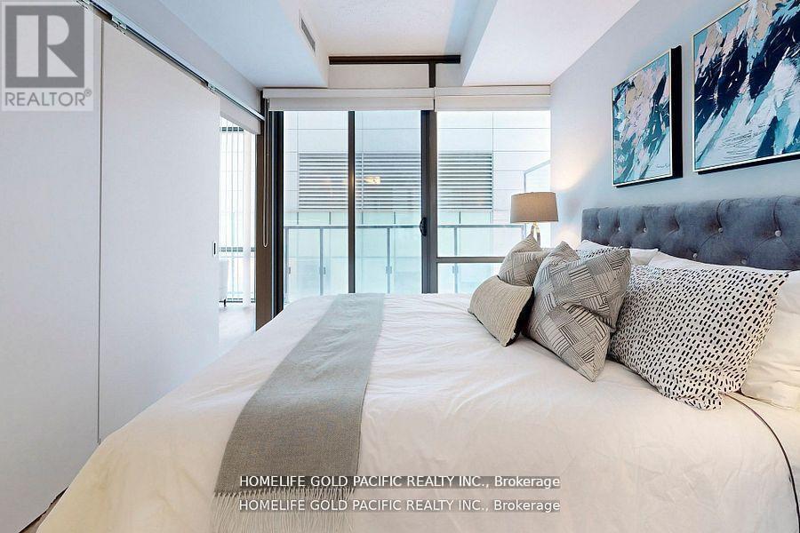 A bedroom with a large bed and a painting on the wall.