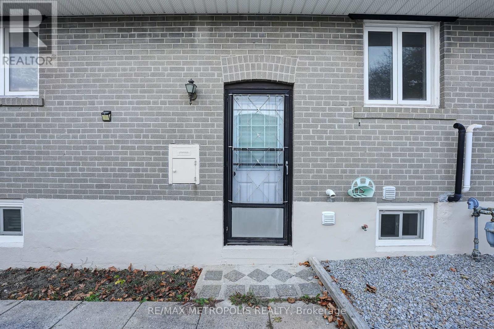 A grey brick house with a black door and windows.