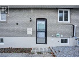 A grey brick house with a black door and windows.