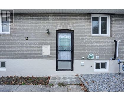 A grey brick house with a black door and windows.