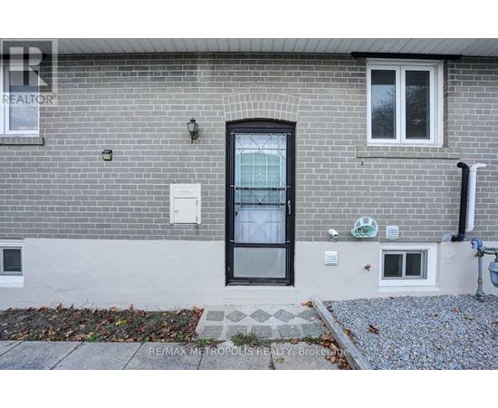A grey brick house with a black door and windows.