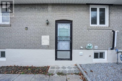 A grey brick house with a black door and windows.