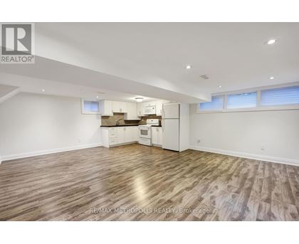 A spacious room with wooden flooring and white walls.