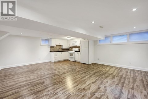 A spacious room with wooden flooring and white walls.