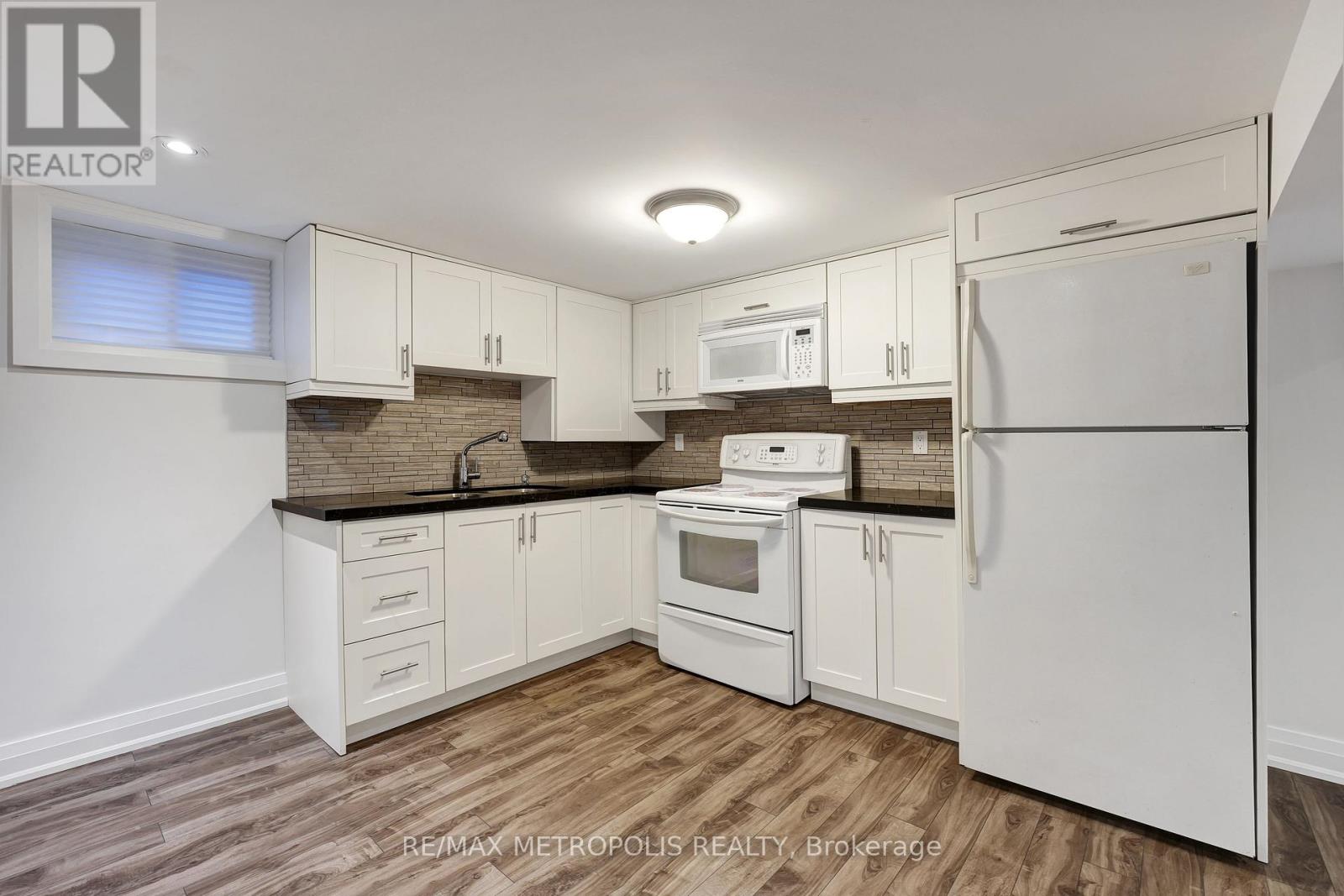 A kitchen with white appliances and wooden floors.