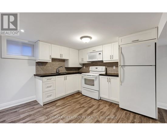 A kitchen with white appliances and wooden floors.