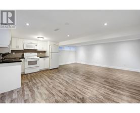 A spacious kitchen with white appliances and wooden flooring.