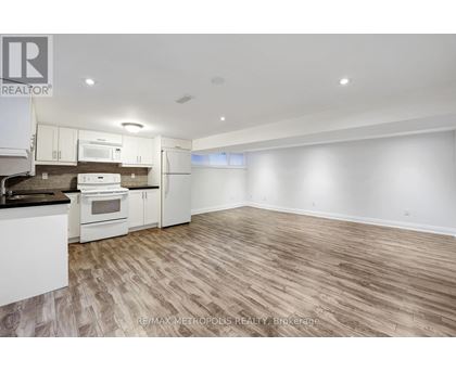 A spacious kitchen with white appliances and wooden flooring.