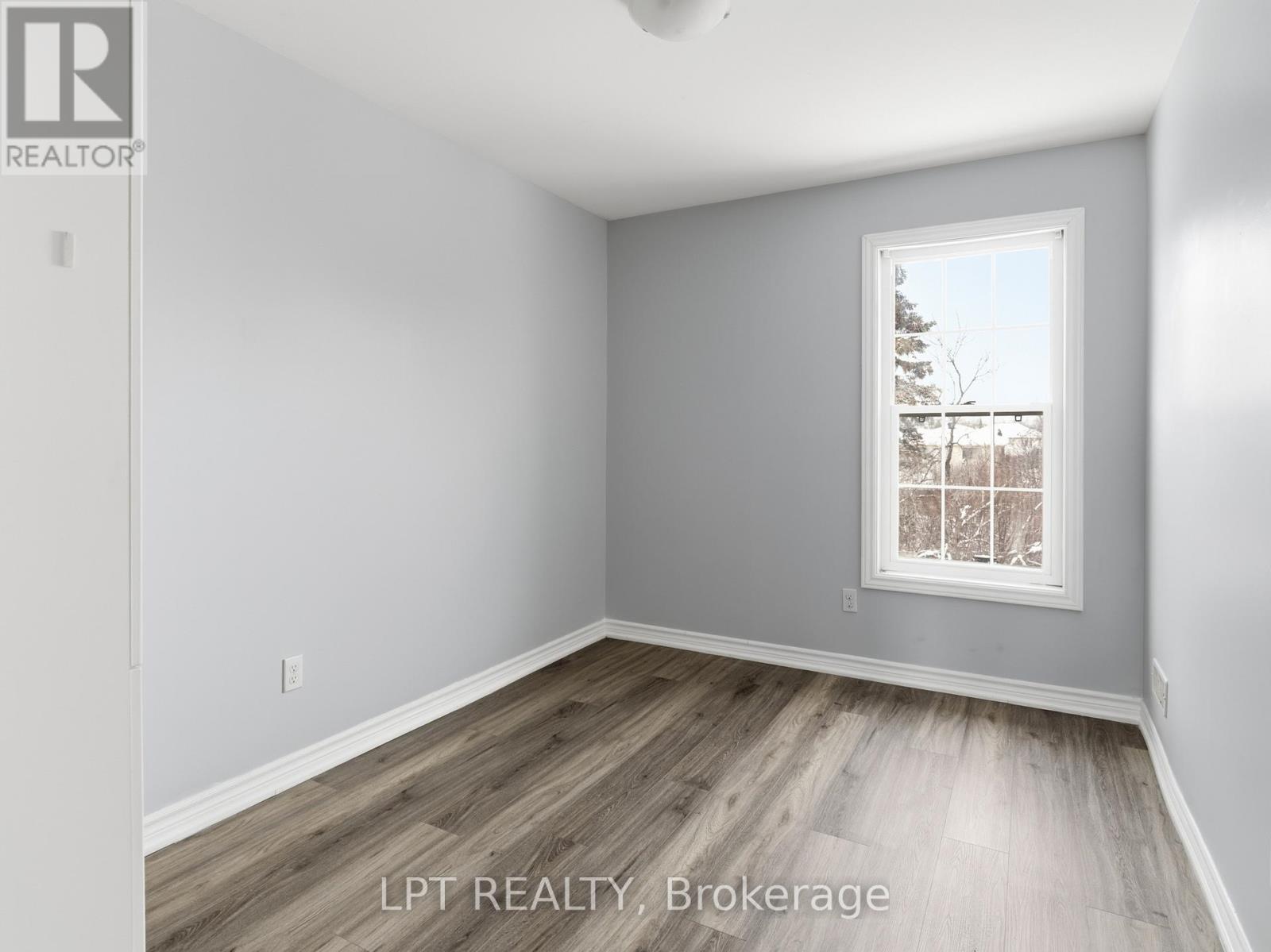 A room with a window showing a view of trees and a building outside.