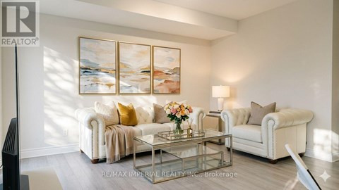 A living room with a white couch, a coffee table, and a painting on the wall.