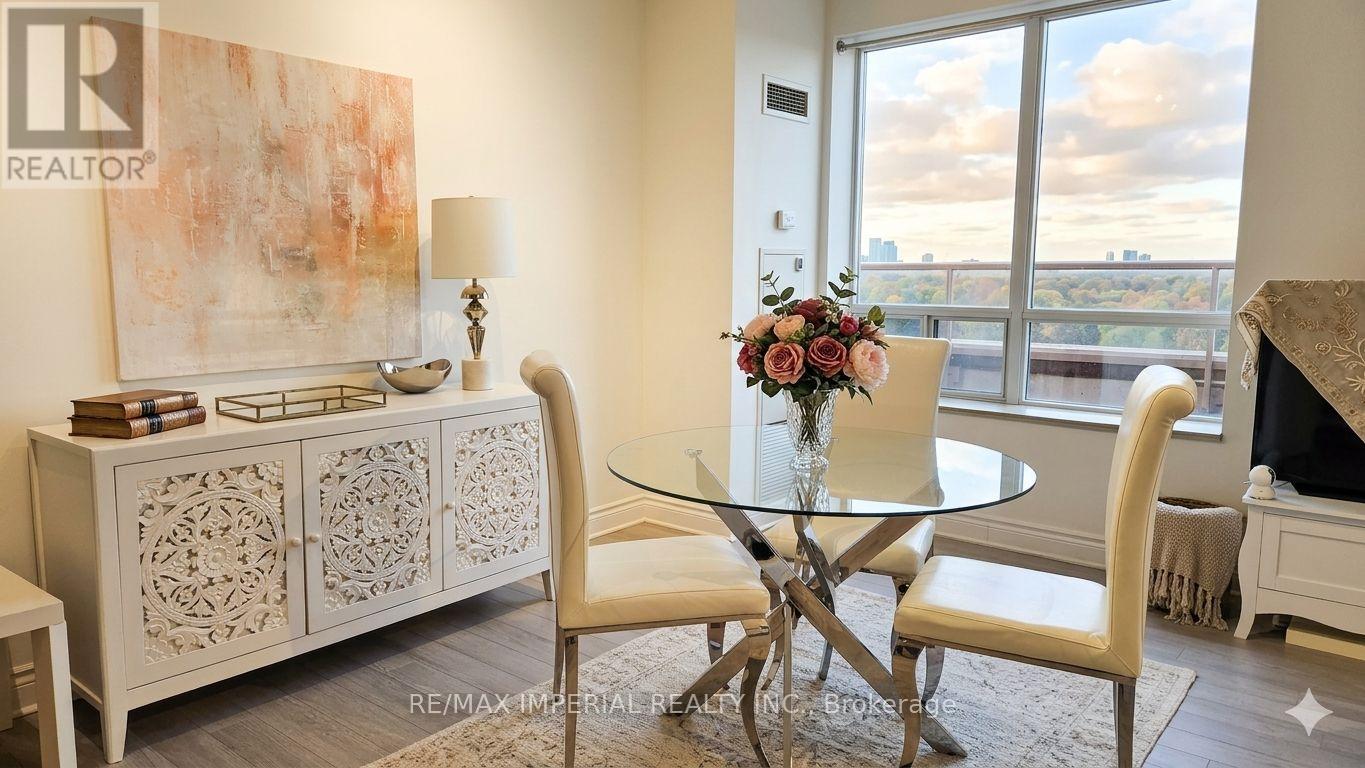 A dining room with a glass table and chairs, a sideboard, and a view of the city.