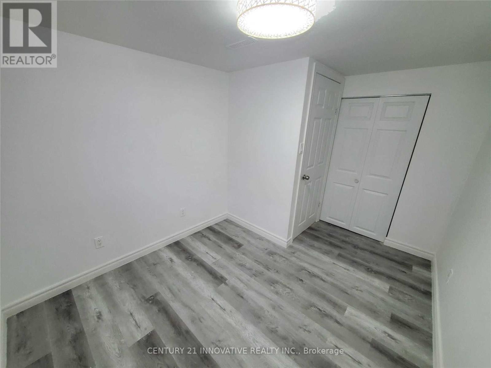 A room with a white door and grey wood flooring.