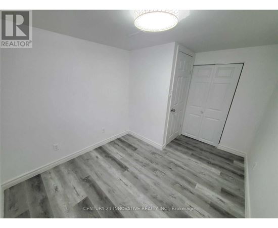 A room with a white door and grey wood flooring.