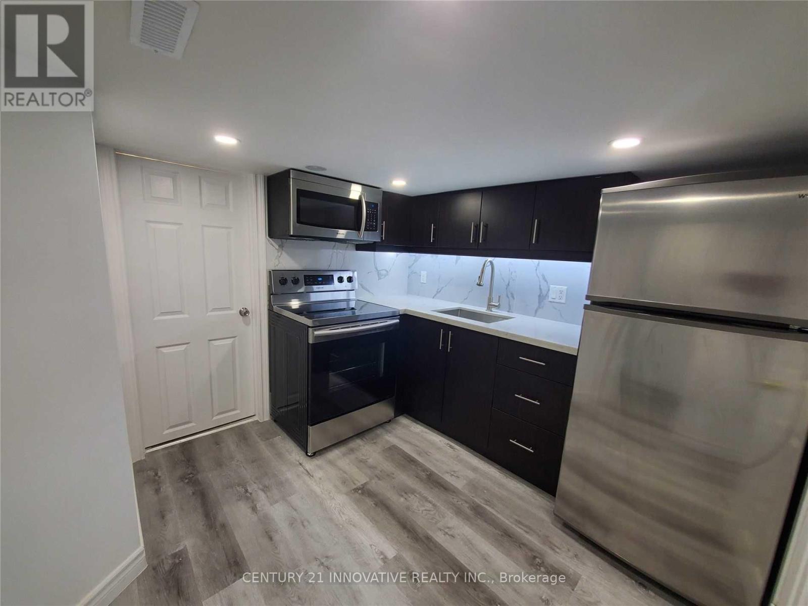 A kitchen with black cabinets and stainless steel appliances.