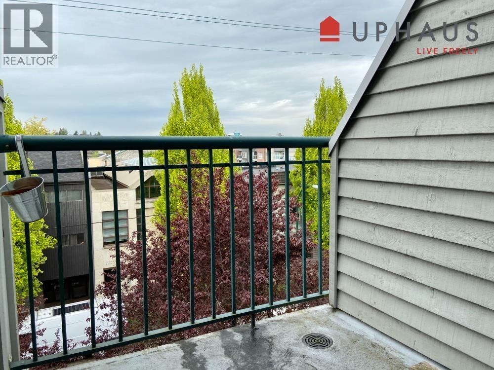 A balcony with a metal railing and a view of a house and trees.