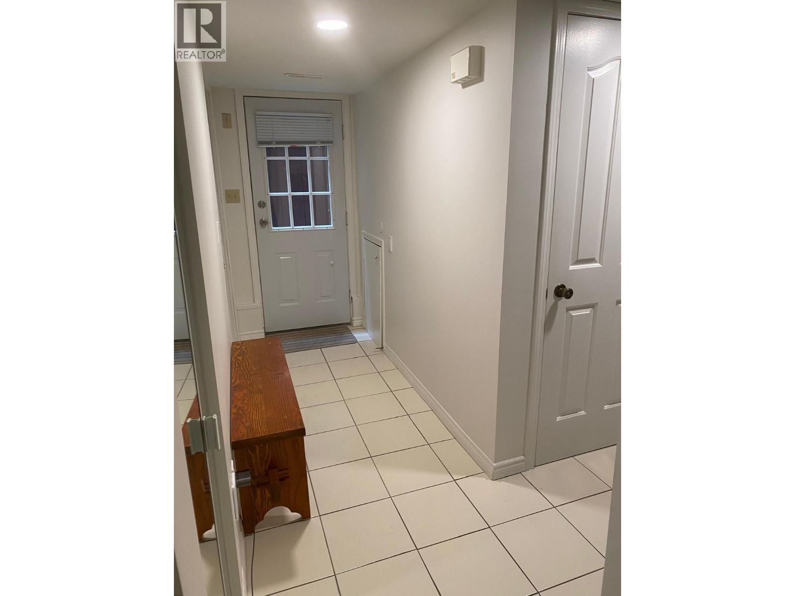 A hallway with a bench and two doors.