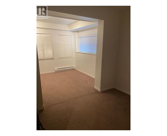 A room with a carpeted floor and a window with blinds.