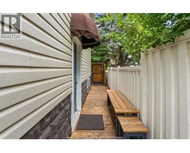 A wooden bench is placed on a wooden platform outside a house.