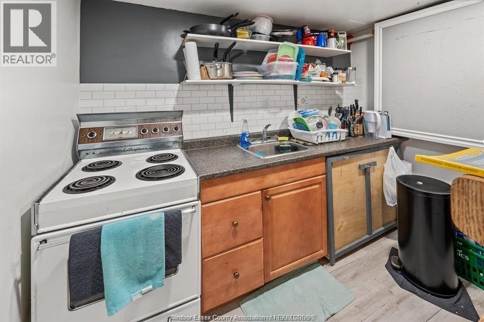A small, cluttered kitchen with a stove, sink, and wooden cabinets.