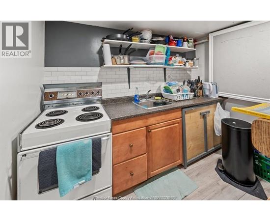 A small, cluttered kitchen with a stove, sink, and wooden cabinets.