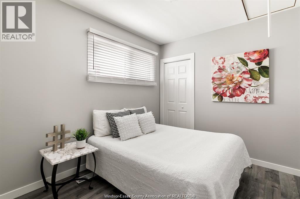 A bedroom with a white bed and a floral picture on the wall.