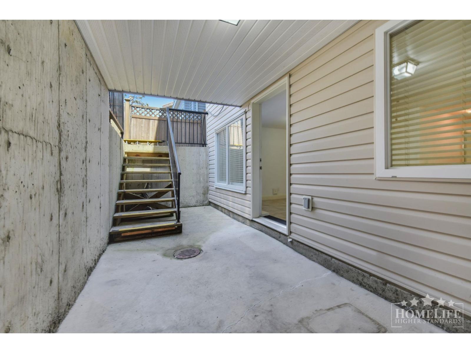 A concrete staircase leads to a balcony outside a home.