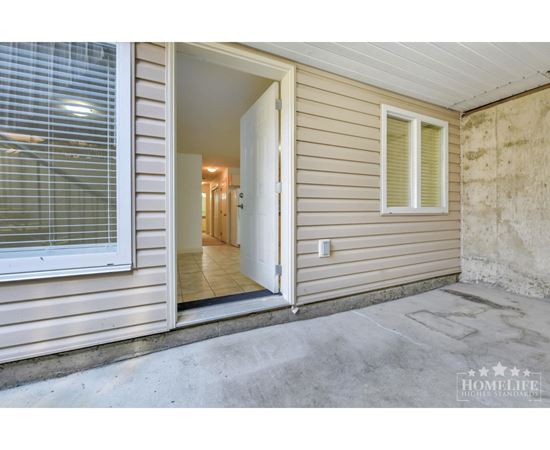 A view of a home's front porch with a door open.