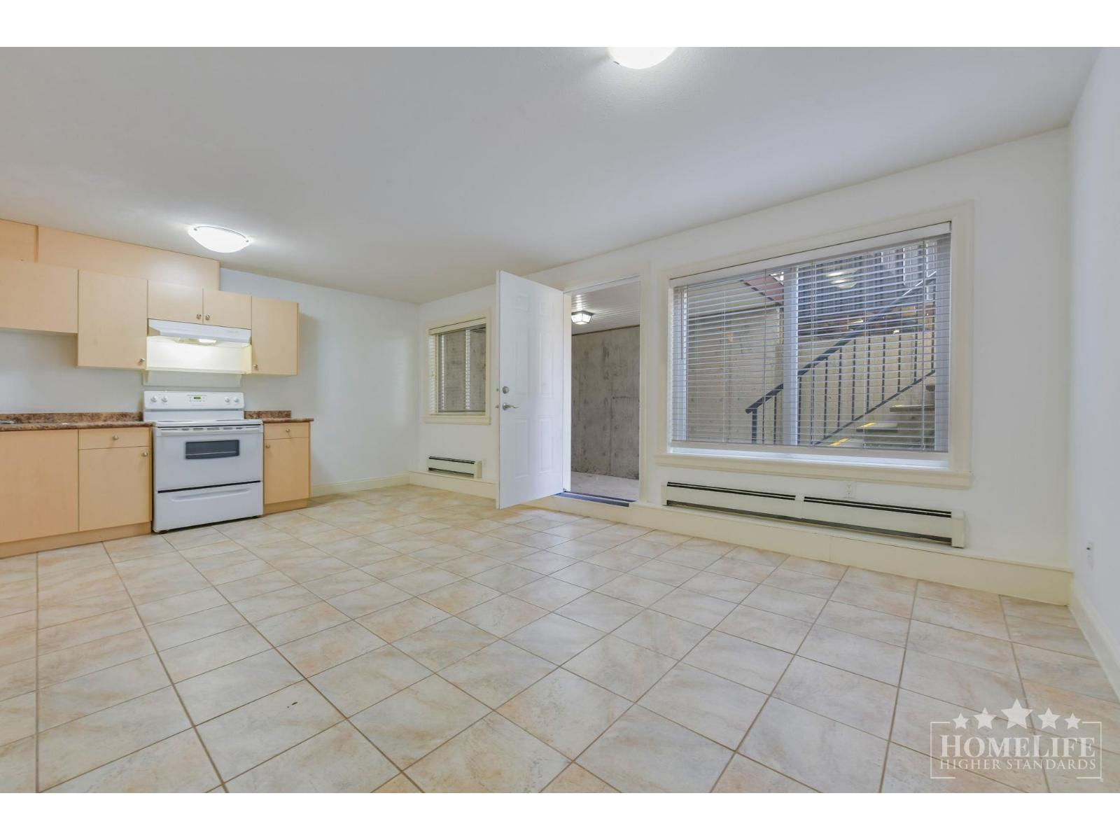 A spacious kitchen with beige cabinets and a tiled floor.