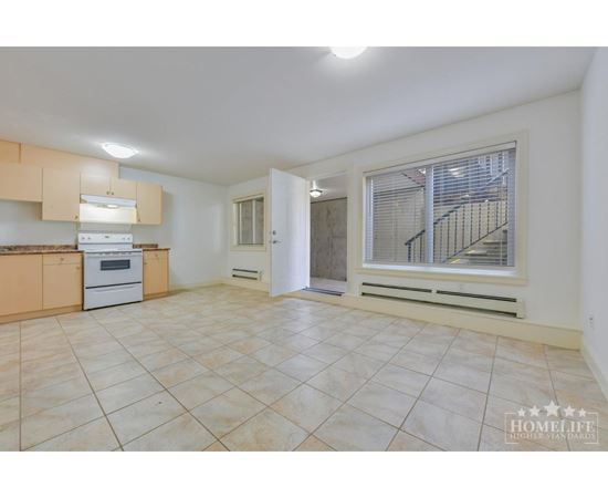 A spacious kitchen with beige cabinets and a tiled floor.