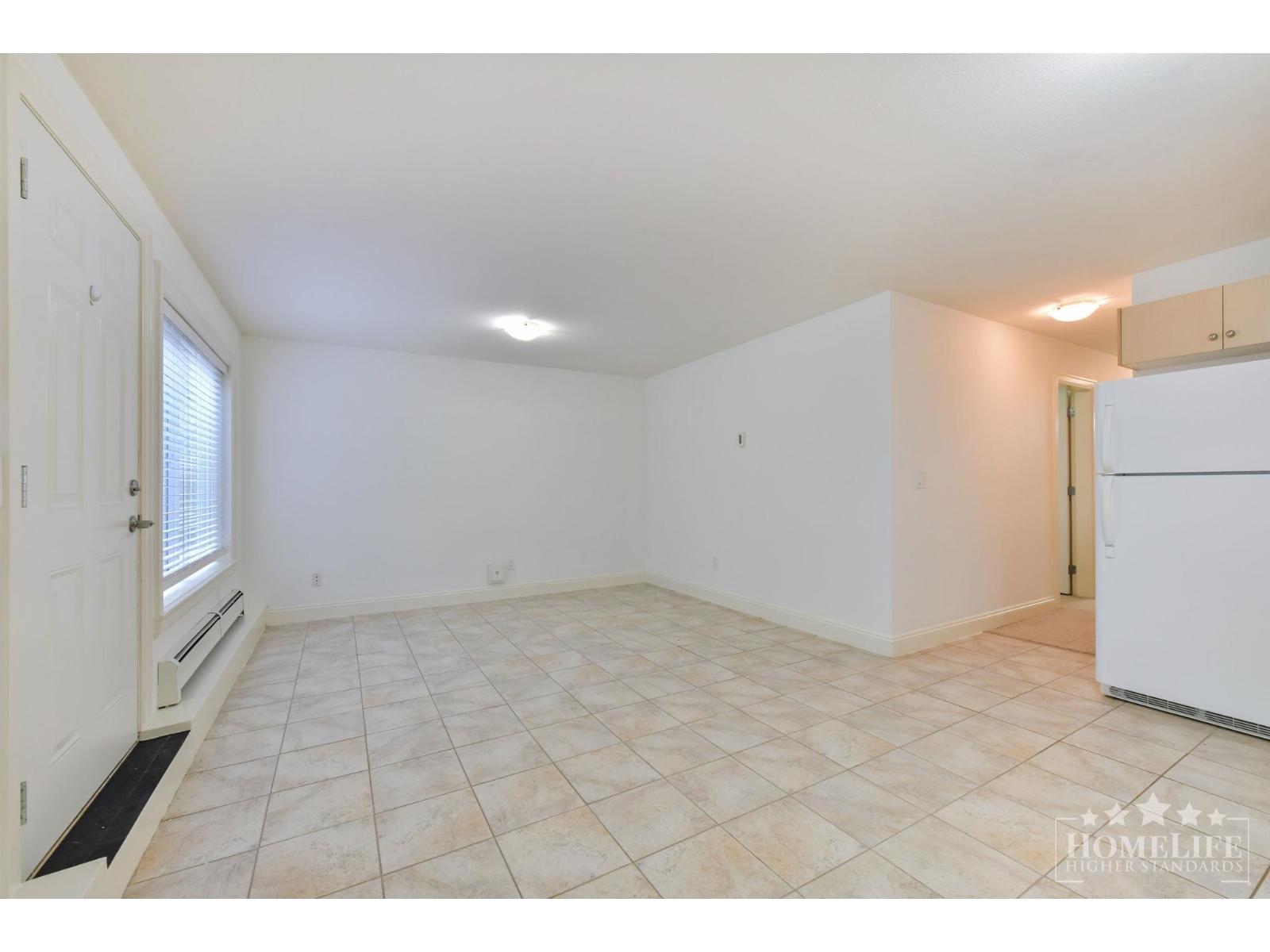 A spacious room with tiled flooring and white walls.
