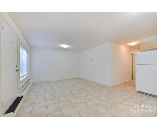 A spacious room with tiled flooring and white walls.