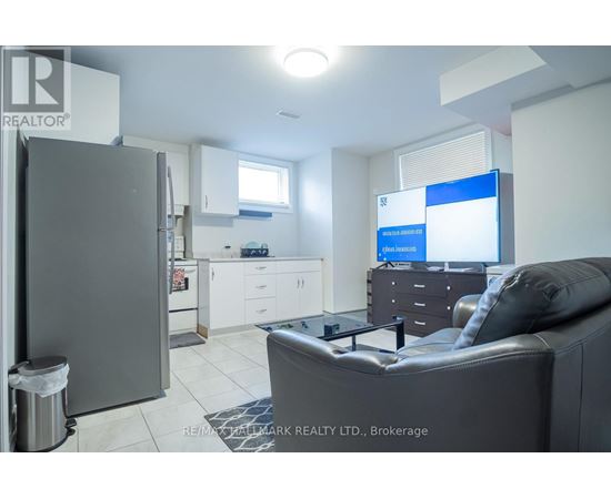 A modern living room with a grey couch and a kitchen area in the background.