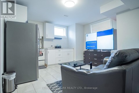 A modern living room with a grey couch and a kitchen area in the background.