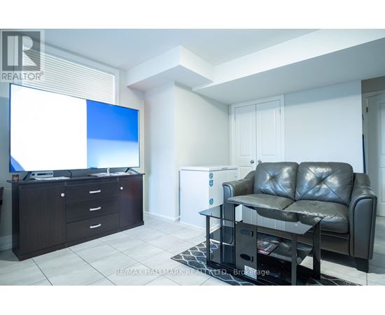 A living room with a black leather couch, a flat screen TV, and a coffee table.