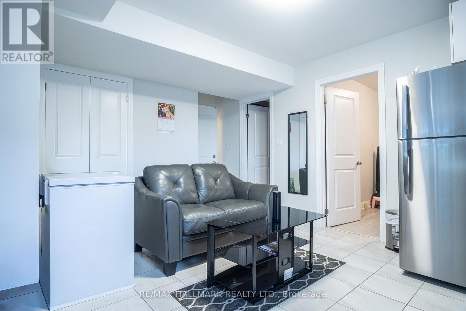 A modern kitchen with a grey leather sofa and a stainless steel refrigerator.