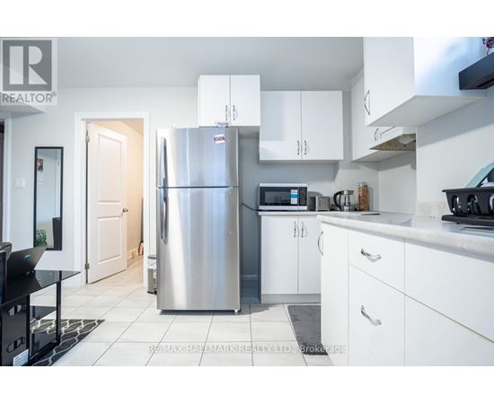 A kitchen with a refrigerator, microwave, and oven.
