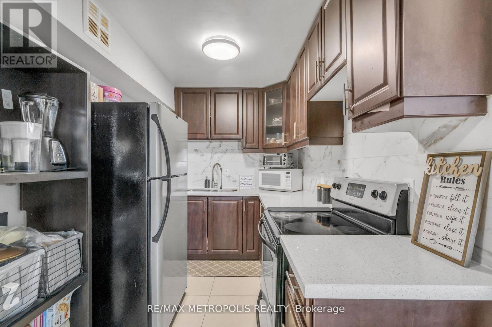 A kitchen with a refrigerator, microwave, oven, and sink.