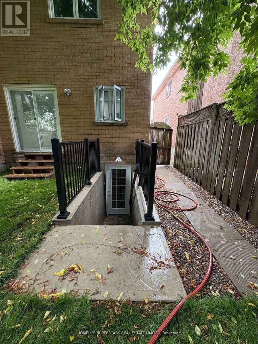 A small black gate is closed to a concrete walkway.