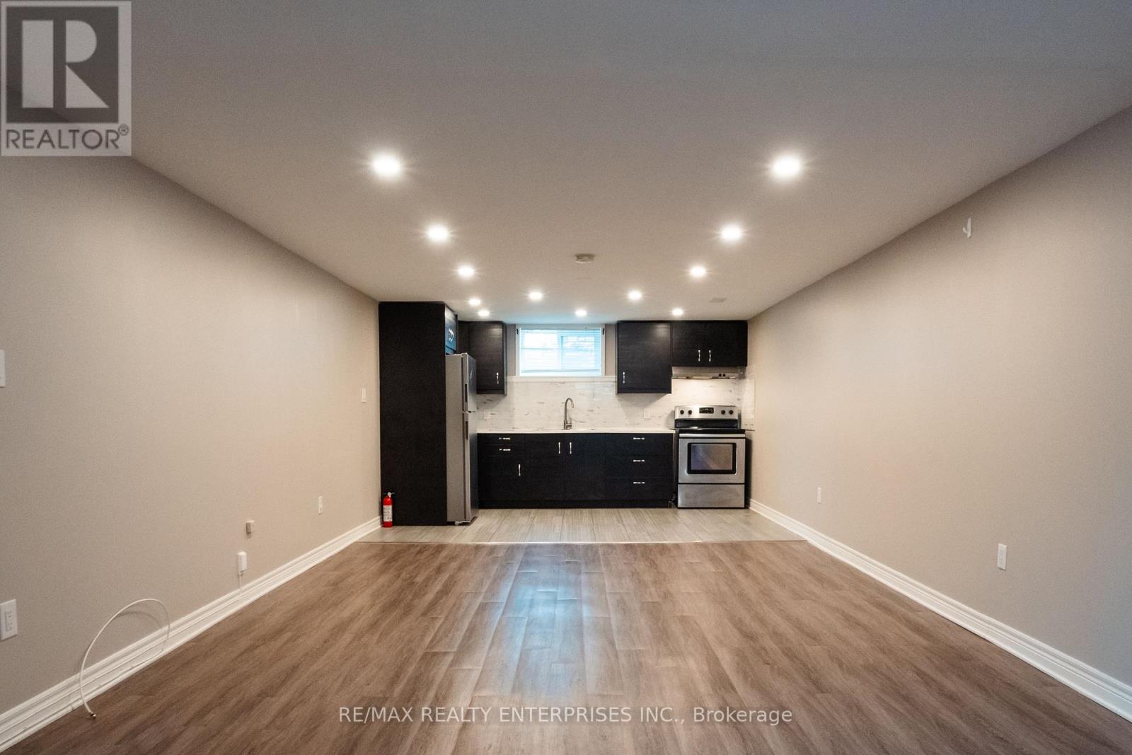 A spacious room with a kitchenette and wooden flooring.