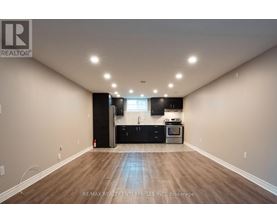 A spacious room with a kitchenette and wooden flooring.