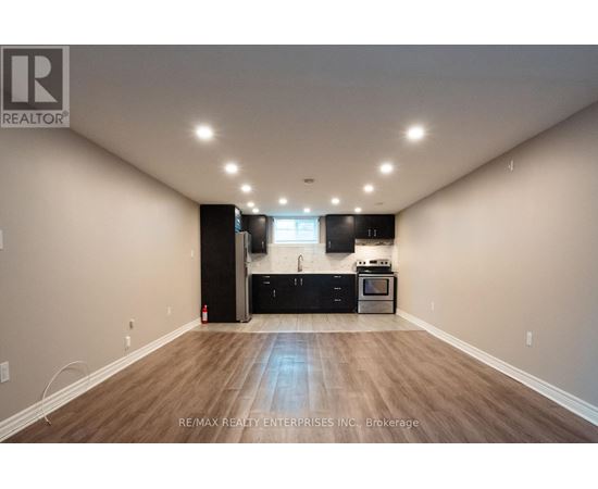 A spacious room with a kitchenette and wooden flooring.