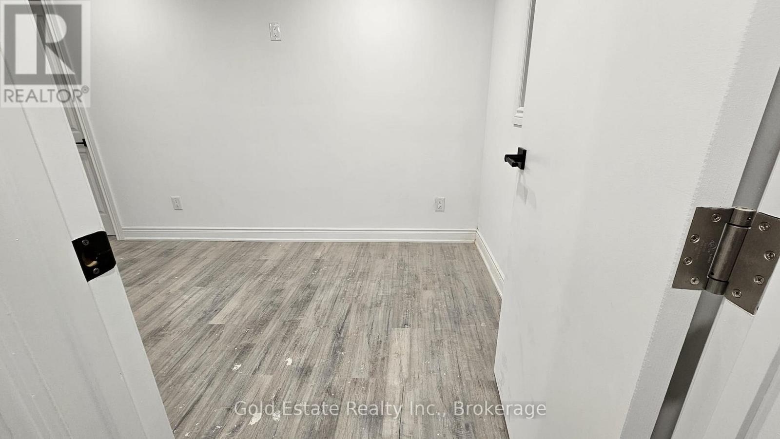 A room with wooden flooring and white walls.