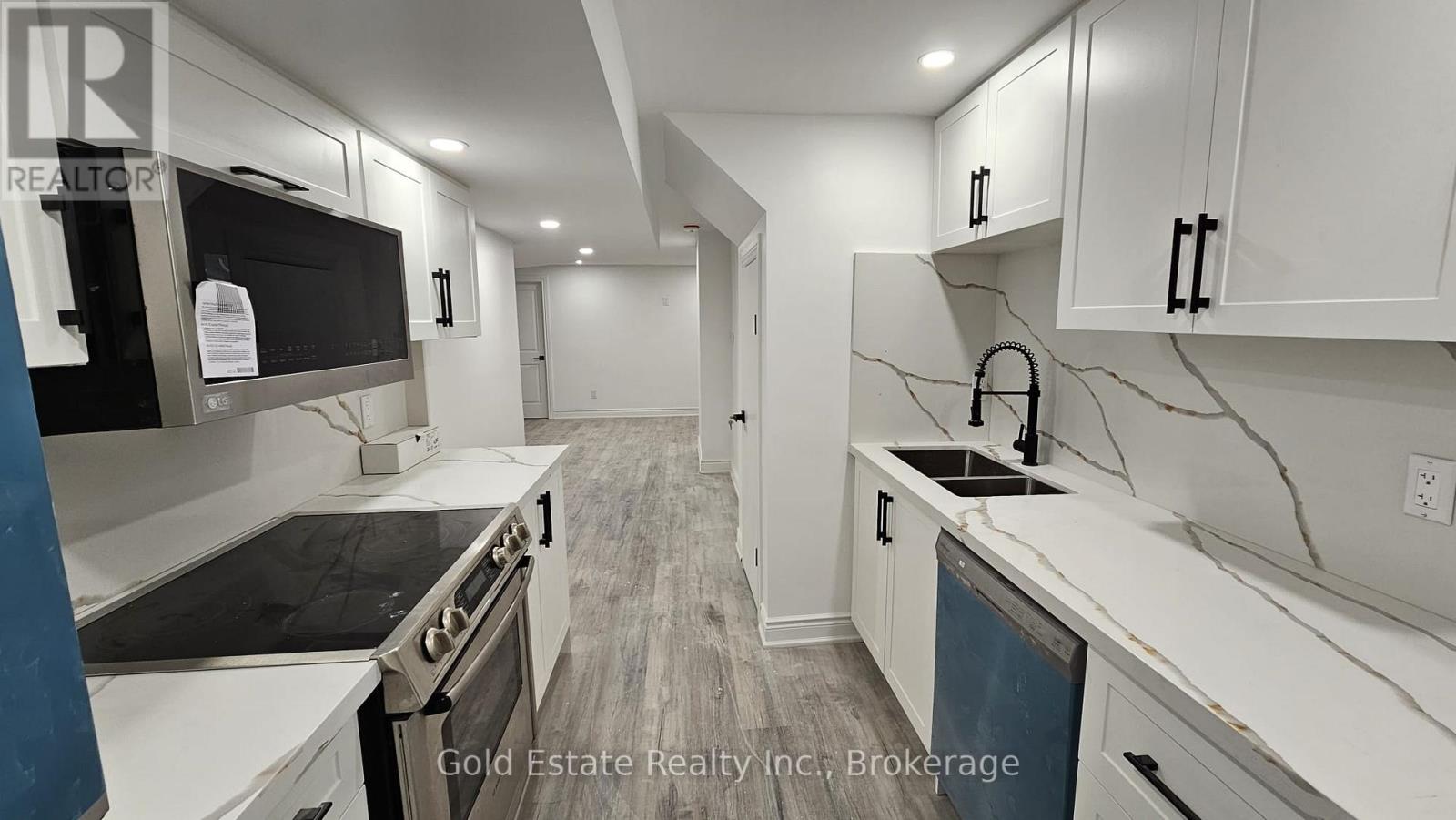 A modern kitchen with white cabinets and a wooden floor.