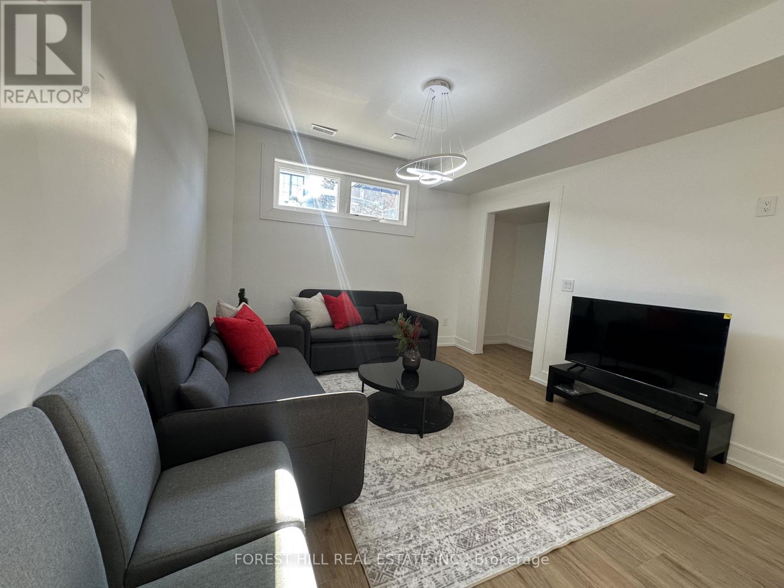 A living room with a grey couch and a black television.