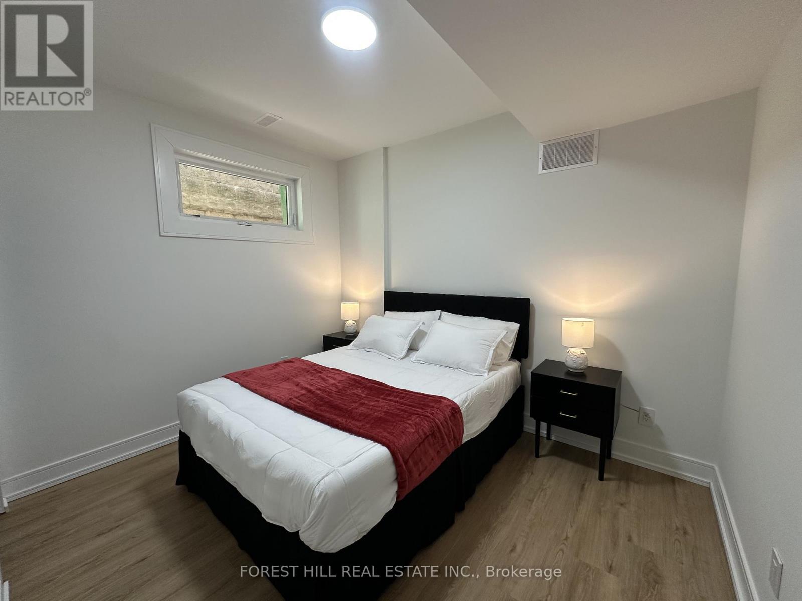 A bedroom with a bed, nightstands, and a painting on the wall.