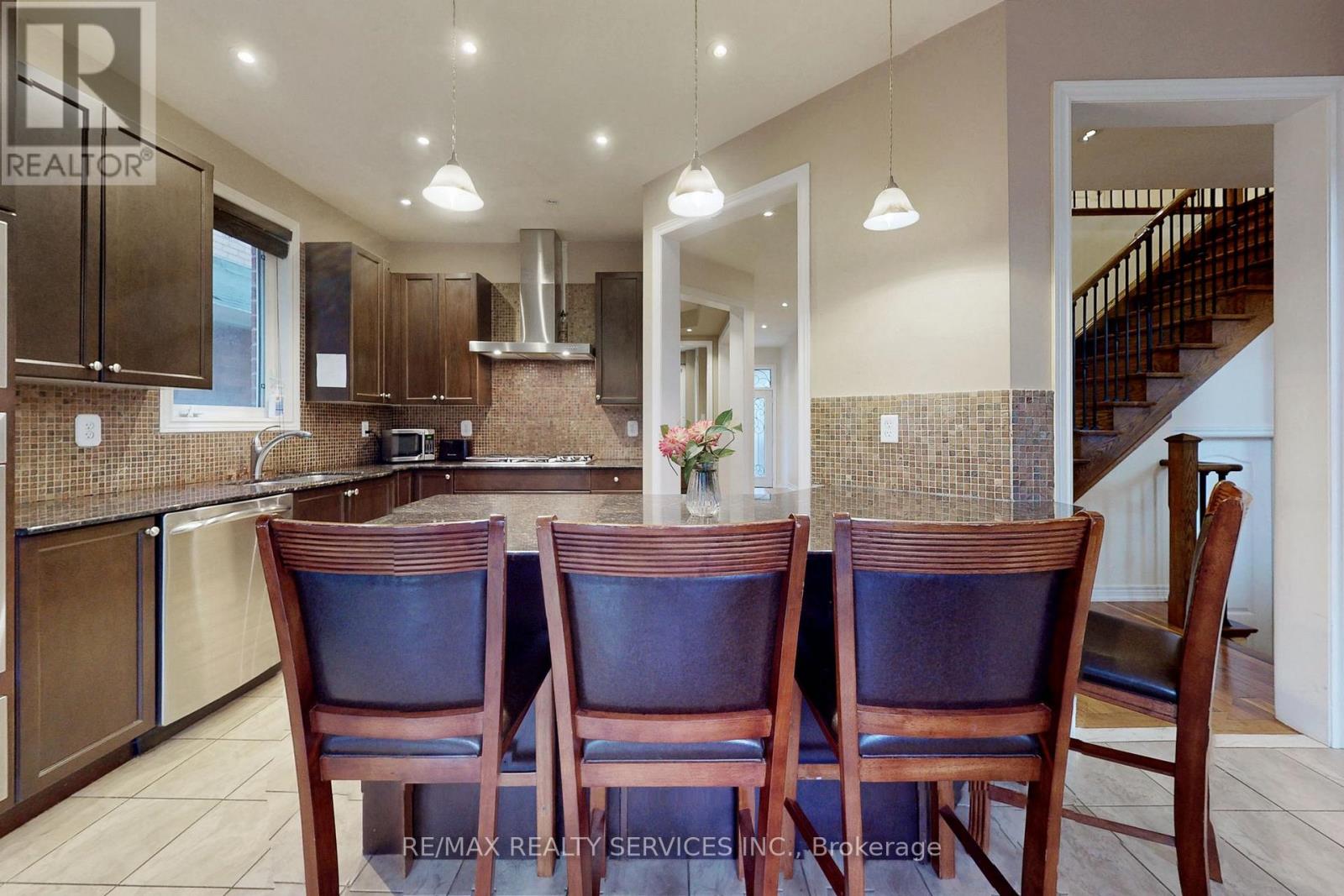 A kitchen with brown chairs and a stainless steel refrigerator.