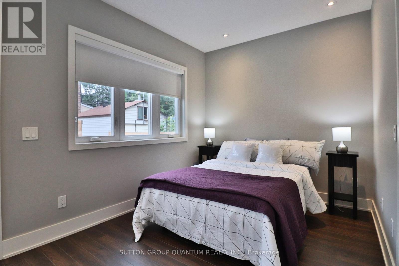 A bedroom with a large bed and a window overlooking a house.