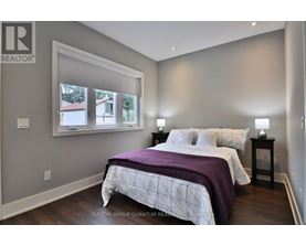 A bedroom with a large bed and a window overlooking a house.